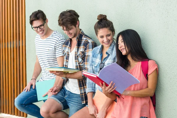 Hip friends leaning against wall and holding notebooks — Stock Photo, Image