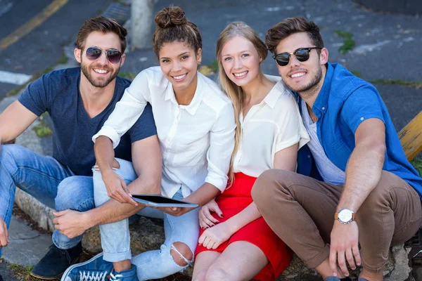 Хип-друзья смотрят на планшет и сидят на тротуаре — стоковое фото