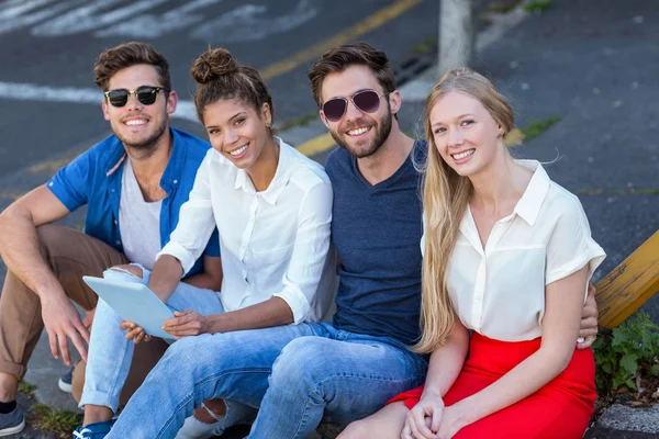 Hüfte Freunde halten Tablet und sitzen auf Gehweg — Stockfoto