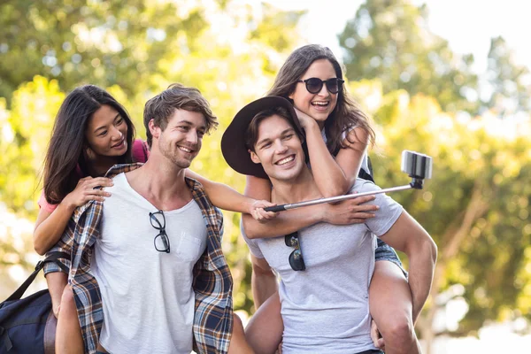 Hip men giving piggy back to their girlfriends — Stock Photo, Image