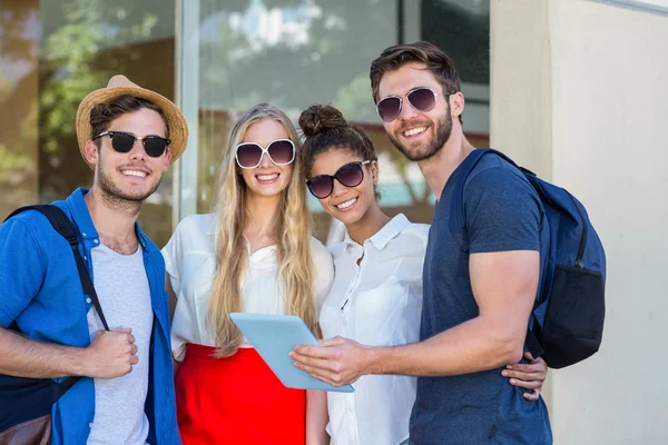 Amigos de la cadera sosteniendo la tableta y sonriendo a la cámara — Foto de Stock