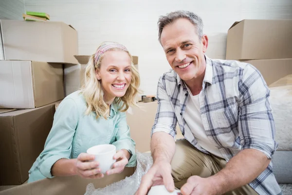 Smiling couple packing mug in a box — Stock Photo, Image