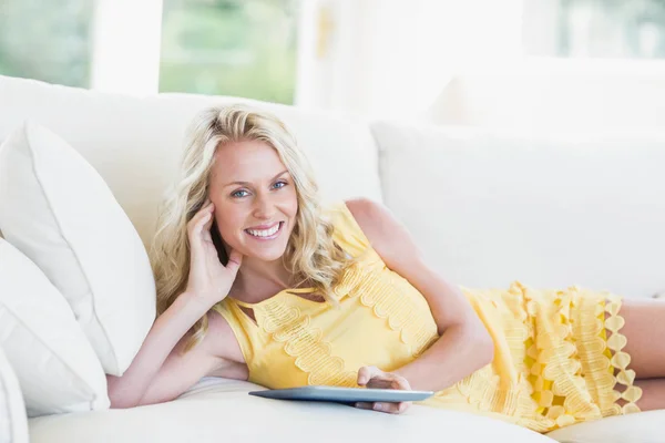 Szczęśliwa kobieta za pomocą tabletu na kanapie — Zdjęcie stockowe