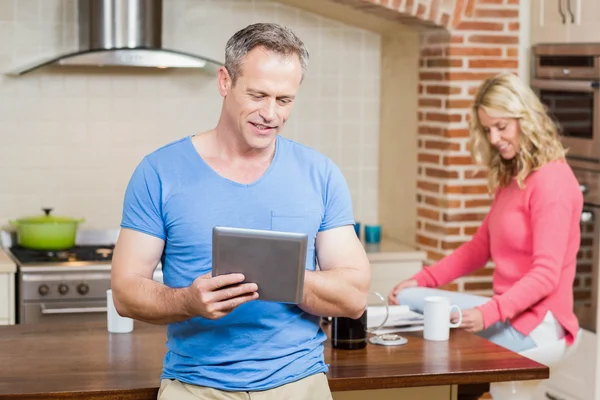 Husband using tablet while wife having breakfast — Stock Photo, Image