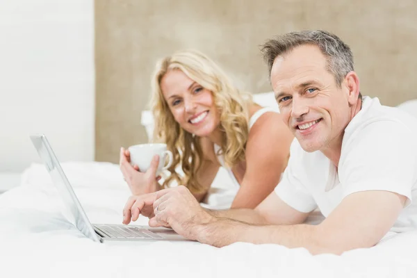 Casal bonito usando laptop na cama — Fotografia de Stock