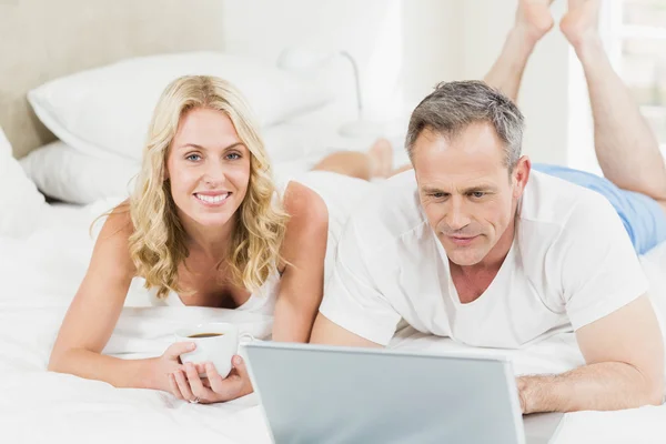 Nettes Paar mit Laptop im Bett — Stockfoto