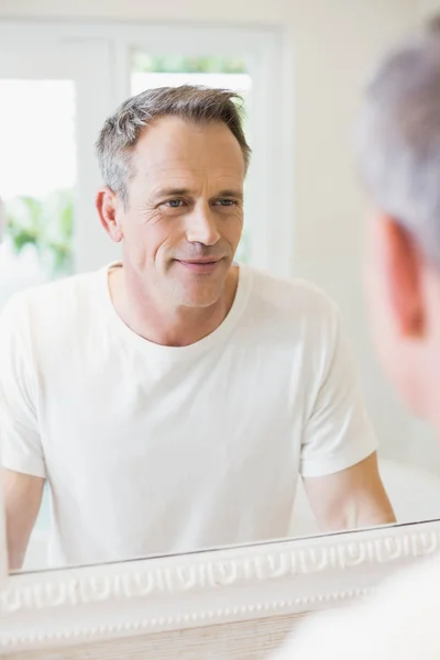 Handsome man looking at himself in the mirror — Stock Photo, Image