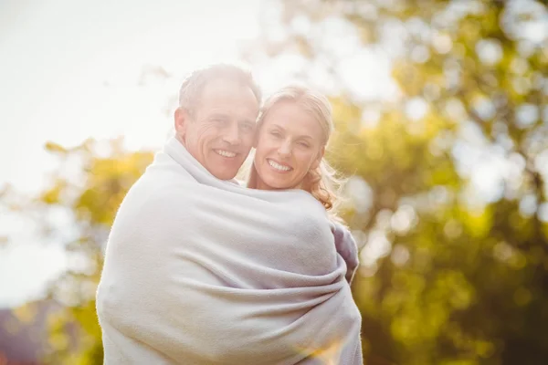 Schattig paar knuffelen met een deken rond — Stockfoto