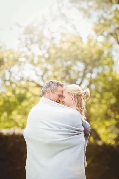 Schattig paar knuffelen met een deken rond — Stockfoto