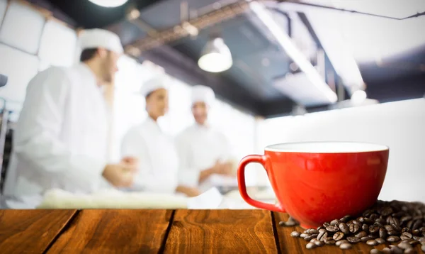 Table en bois contre les grains de café et tasse — Photo