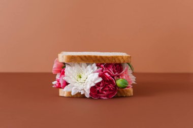 Yaratıcı kavramsal sandviç pastel arka planda çeşitli çiçeklerle yapılır. En az yaz yemeği teması.