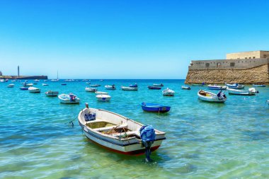 Santa CatalinaCastillo de Santa Catalina yakınlarındaki Atlantik Okyanusu 'nun masmavi sularında ufukta deniz feneri olan balıkçı tekneleri, Cadiz, İspanya - 20 Mayıs - 2025