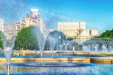 Güneşli bir günde mavi gökyüzü, Bükreş, Romanya - 17 Mayıs - 25 Mayıs 2025 tarihlerinde Parlemento Palatul Parlamentului Sarayı ve çeşmeleri