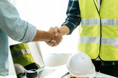 Mühendis, mimar, inşaat işçisi ekip iş yeri masasındaki proje sözleşmesi üzerine titreyen el sıkışması inşaat alanındaki toplantı odası ofisi, müteahhit, ortaklık, inşaat konsepti