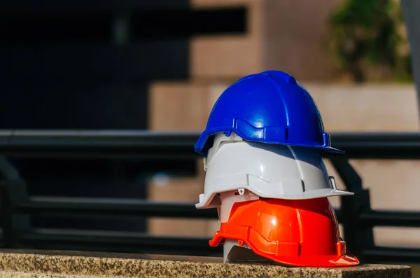 Safety First. white, orange and blue safety helmet stacked in construction site building, safety equipment, business, industry and construction concept