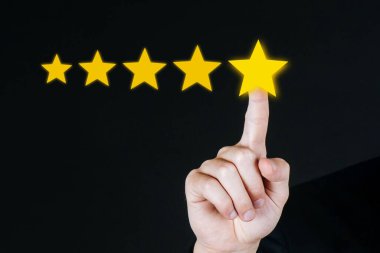 Çok iyi. 5 yıldız puanı. iş adamı eli görsel ekranda beş yıldız tuşuna basarak koyu arkaplan, iyi deneyim, olumlu düşünce, müşteri geribildirim kavramını iyi değerlendirmek için