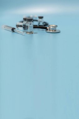 Coronavirus aşı şişesi, stetoskop ve tıbbi ekipman cadı kopya alanı mavi arka plan, virüs önleme, aşı, tıbbi teknoloji, araştırma laboratuvarı, covid-19 aşı konsepti