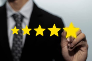 Yüksek kalite. İyi derecelendirme, dijital pazarlama, iyi deneyim, müşteri değerlendirmesi ve müşteri geribildirim kavramını gözden geçirmek için takım elbiseli müşteri müşterisi beş yıldız tuşuna işaret ediyor.