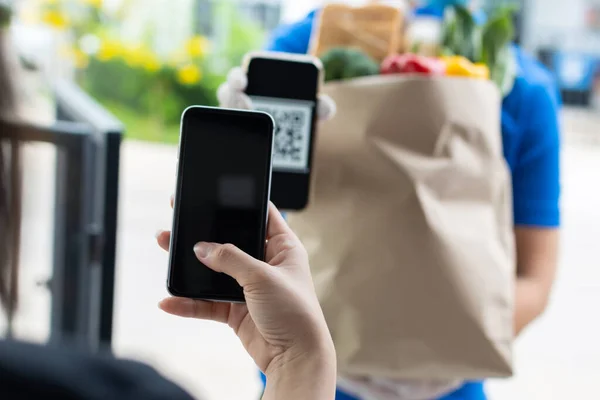 woman hand customer using digital mobile phone scan QR code paying for buy fresh food set bag from food delivery service man, express delivery, digital payment technology, fast food delivery concept