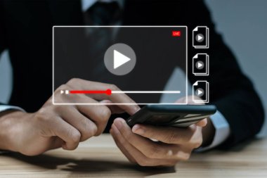 İş adamı video içeriğini izliyordu. Cep telefonundan çevrimiçi yayın yapıyordu. Sanal toplantı, sanal iş reklamcılığı, video pazarlama, televizyon programı, çevrimiçi çalışma, dijital pazarlama teknolojisi.