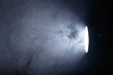 El feneri ya da dumanın içindeki spot ışığı. Karanlık bir arkaplanda ışık huzmesi. Sis