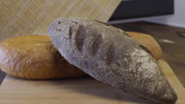 Schwarzbrot Liegt Auf Einem Schneidebrett Zusammen Mit Einem Laib Weißbrot — Stockvideo