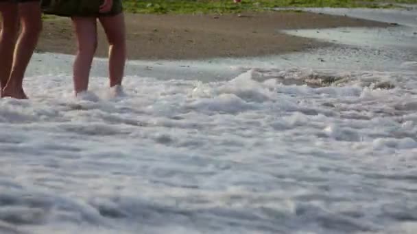 Άνθρωποι στέκονται με γυμνά πόδια στο νερό στην παραλία — Αρχείο Βίντεο