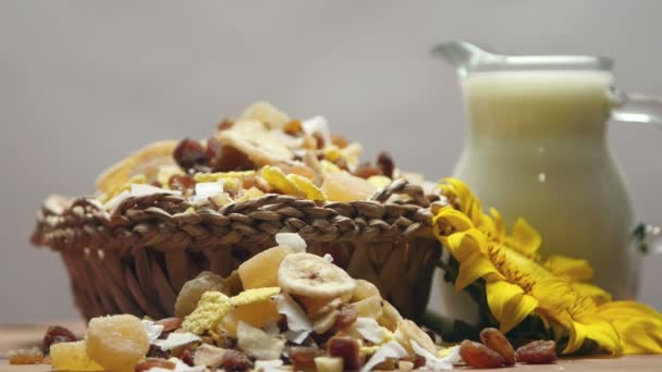 Cereal, dried fruit and jug of milk on wooden table, rotating — Stock Video