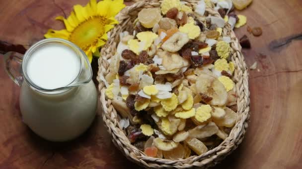 Cereais, frutas secas e jarro de leite na mesa de madeira, girando — Vídeo de Stock