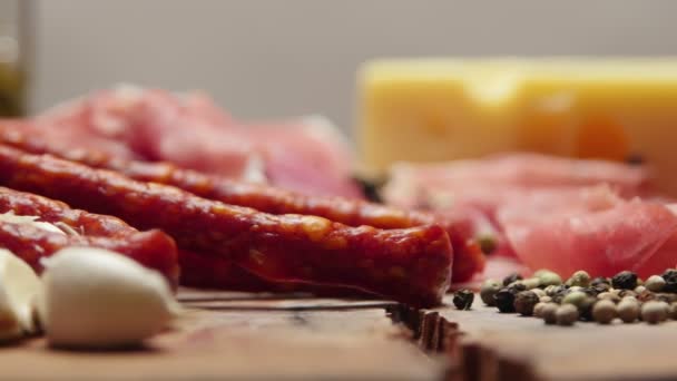 Крупним планом тонкі скибочки прошутто з сухими сирими ковбасками і свинячим сиром на дерев'яній обробній дошці — стокове відео