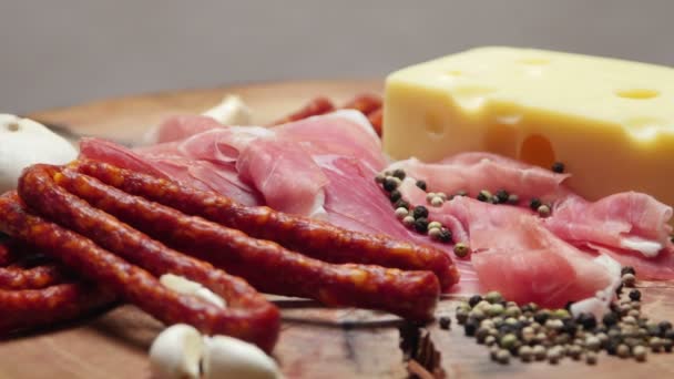 Primo piano di sottili fette di prosciutto con salsicce crude secche e formaggio svizzero sul tagliere di legno — Video Stock