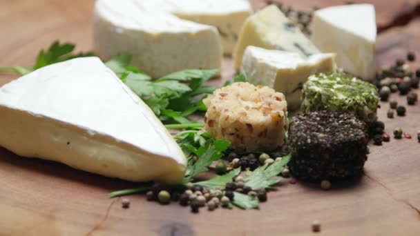 Variétés de fromage aux herbes et grains de poivre sur une planche de bois, tournant — Video