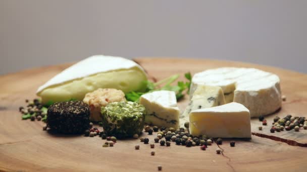 Variétés de fromage aux herbes et grains de poivre sur une planche de bois, tournant — Video