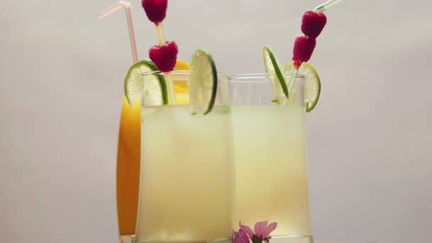Een glas van natuurlijke sinaasappelsap en twee glazen limonade, roterende — Stockvideo