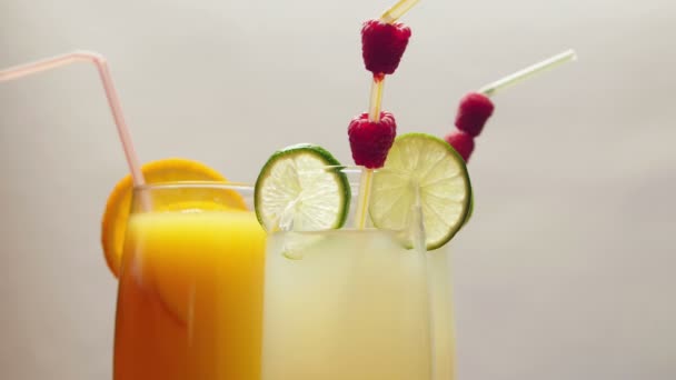 Un vaso de jugo de naranja natural y dos vasos de limonada, girando — Vídeo de stock