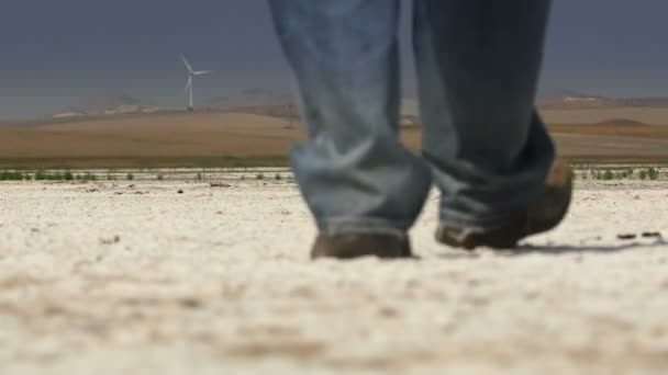 Человек идет по высохшему солёному озеру под палящим солнцем — стоковое видео