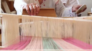 Bir kadın eski bir tahta dokuma tezgahında dokuma