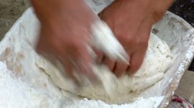 Yaşlı kadın ahşap bir kapta hamur yoğurma