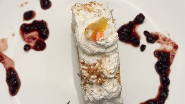 Торт со взбитыми сливками на белой тарелке, вращающийся — стоковое видео