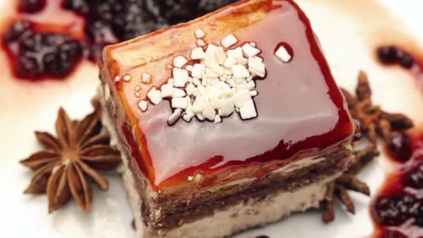 Закрыть карамельный торт с белым шоколадом на белой пластине, вращающийся — стоковое видео