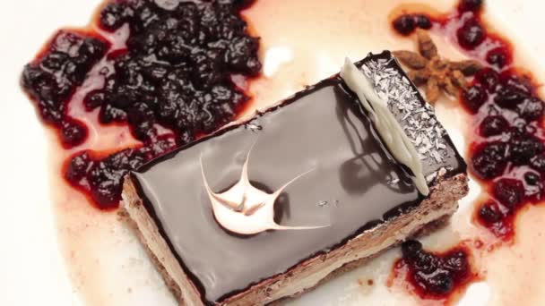 Крупним планом шоколадний торт на білій тарілці, що обертається — стокове відео