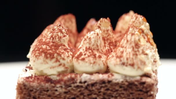 Közelről egy tiramisu torta fehér tányérra, forgatható