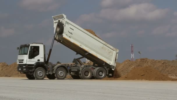 Dumper caminhão descarregamento de solo no canteiro de obras durante obras rodoviárias — Vídeo de Stock