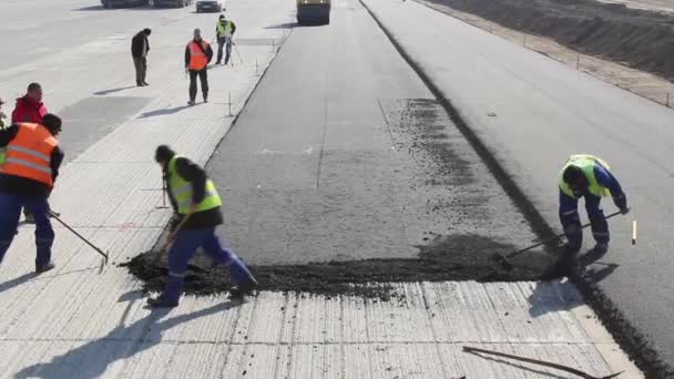 Construction workers leveling fresh asphalt pavement — Stock Video