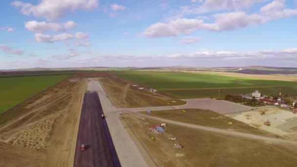 Tracked paver laying fresh asphalt pavement on an airport runway, aerial view — Stock Video