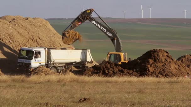 Bandgående grävmaskin deponerar jord till en dump truck — Stockvideo