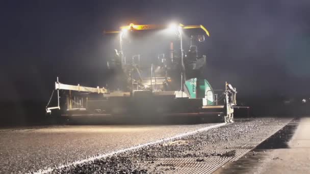 Pavimentadora de seguimiento que pone pavimento de asfalto fresco por la noche — Vídeos de Stock