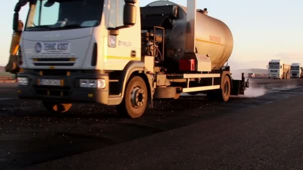 Camión esparcidor de aceite aplicando tachuelas sobre una superficie en preparación para pavimentar — Vídeo de stock