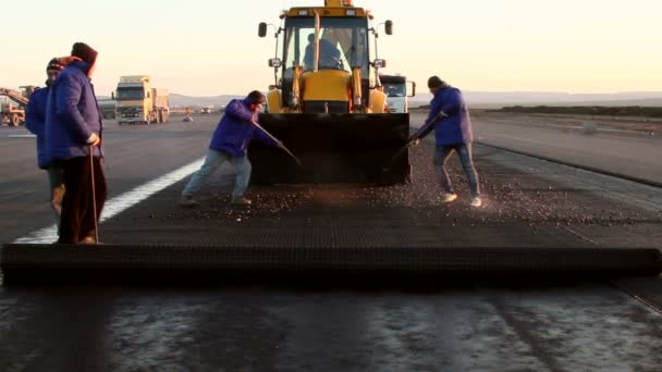 Workers applying reinforcement mesh on a surface in preparation for paving — Stock Video