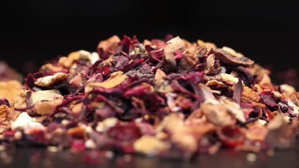 Pile de thé aux fruits avec pétales et fruits secs isolés sur noir, tournant — Video